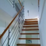 Wangentreppe in weiß, mit Eichenstufen und einem Geländer aus Edelstahl