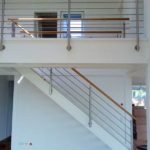 Wangentreppe in weiß, mit Eichenstufen und einem Geländer aus Edelstahl